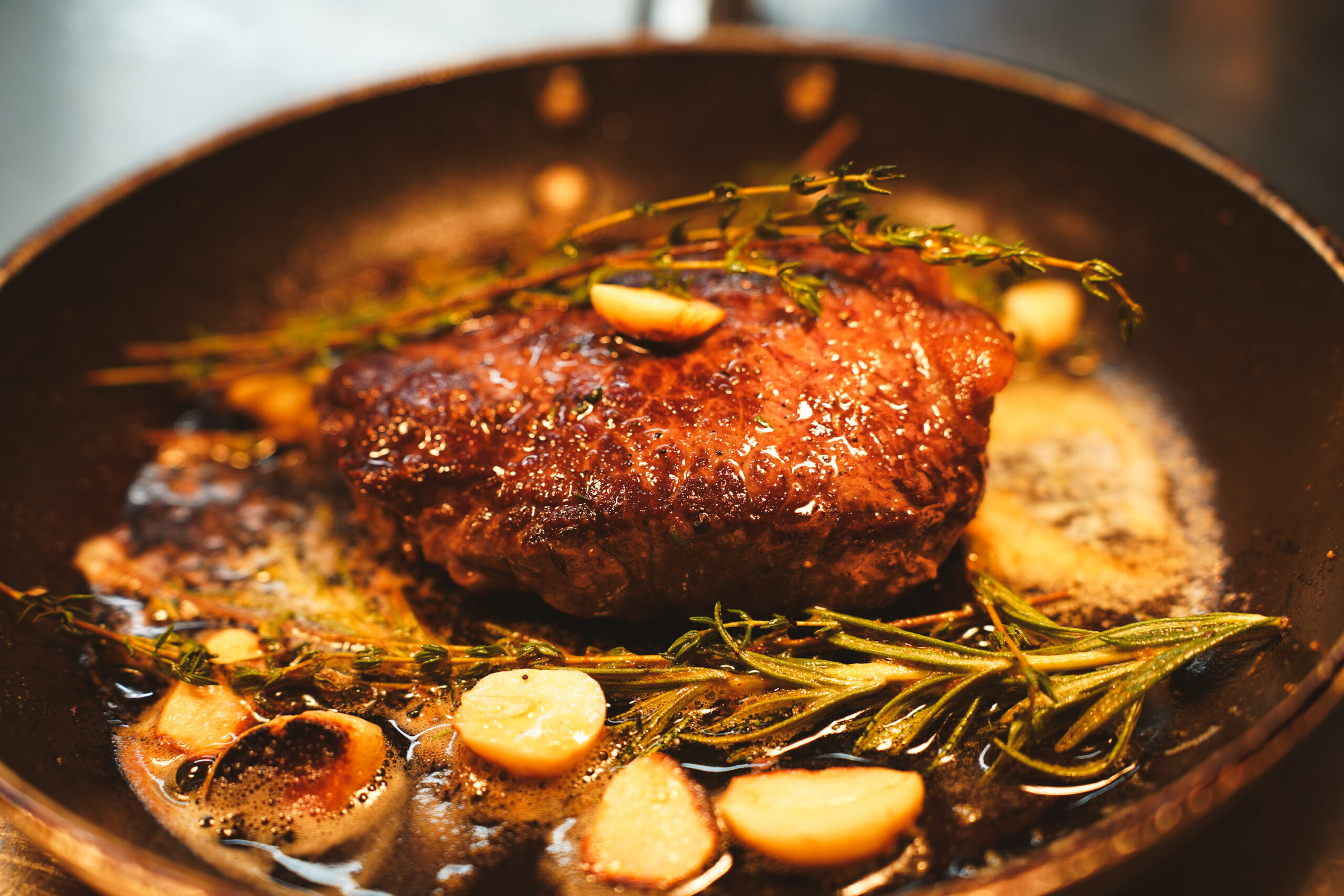 Steak in a pan with garlic and herbs